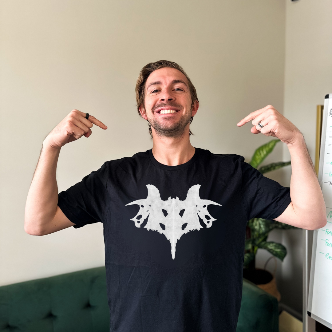 Man wearing a black t-shirt with a white graphic design, pointing at the shirt.