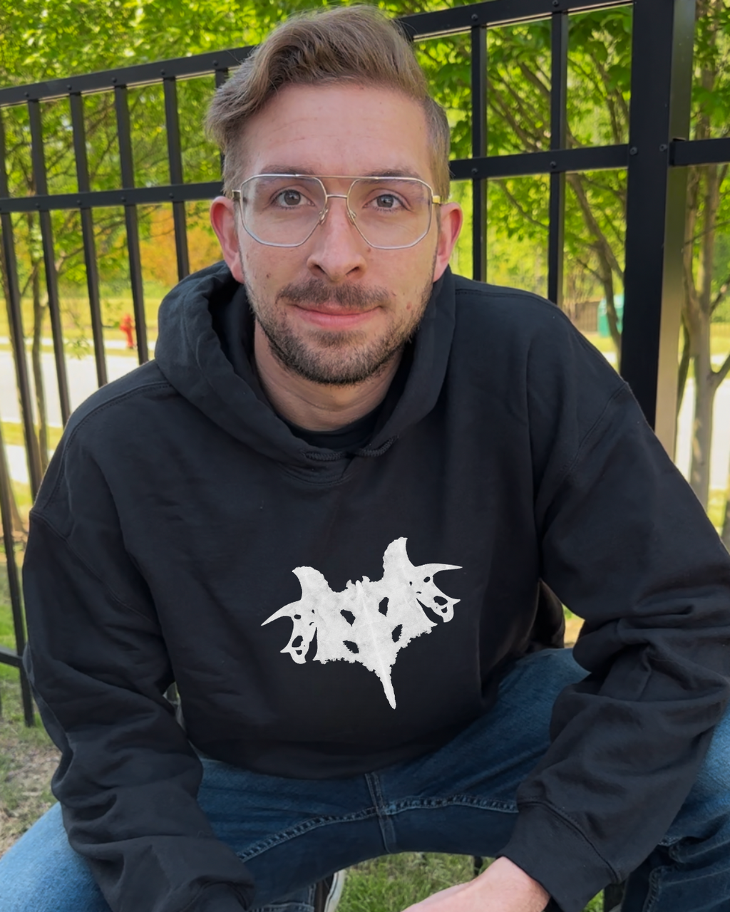 Man wearing a black hoodie with a white graphic design outdoors